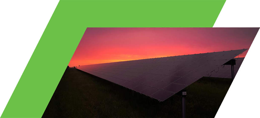 A row of solar panels silhouetted against a vibrant sunset sky.
