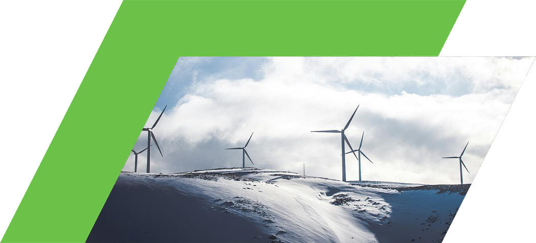 A row of wind turbines stands on a snowy hill under a cloudy sky.