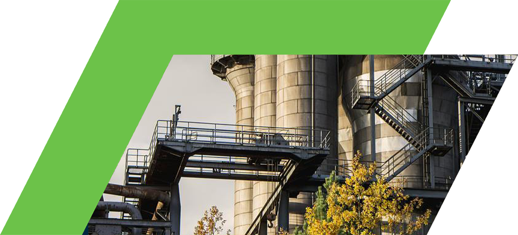 Industrial silos surrounded by autumn foliage under a cloudy sky.
