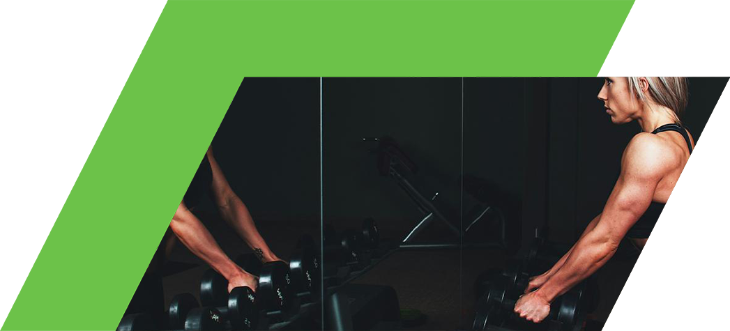 A fit woman with blonde hair is lifting weights in front of a mirror in a gym.