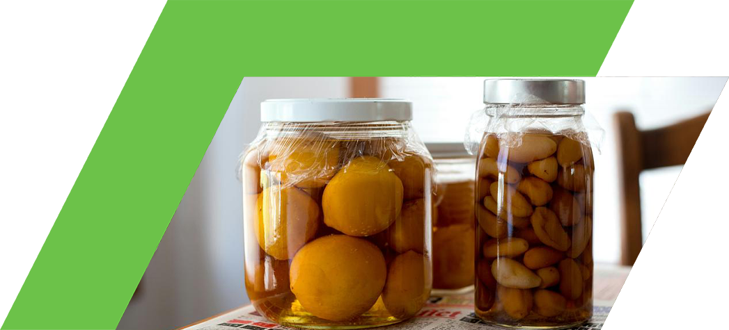Jars filled with preserved fruit sit on a newspaper-covered table.