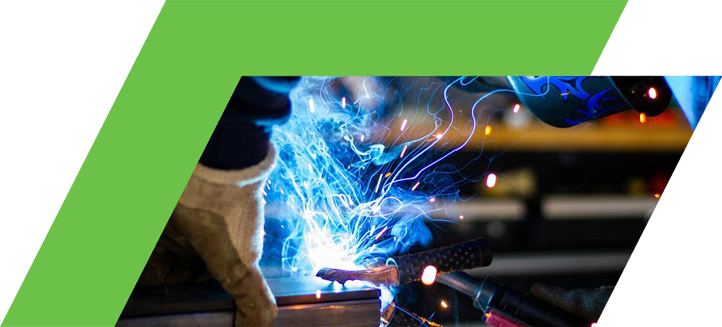 A welder in protective gear creates sparks and bright blue light while welding metal.