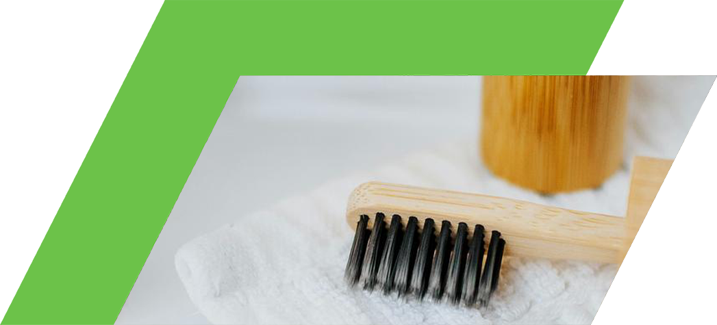 A bamboo toothbrush and container resting on a soft towel.