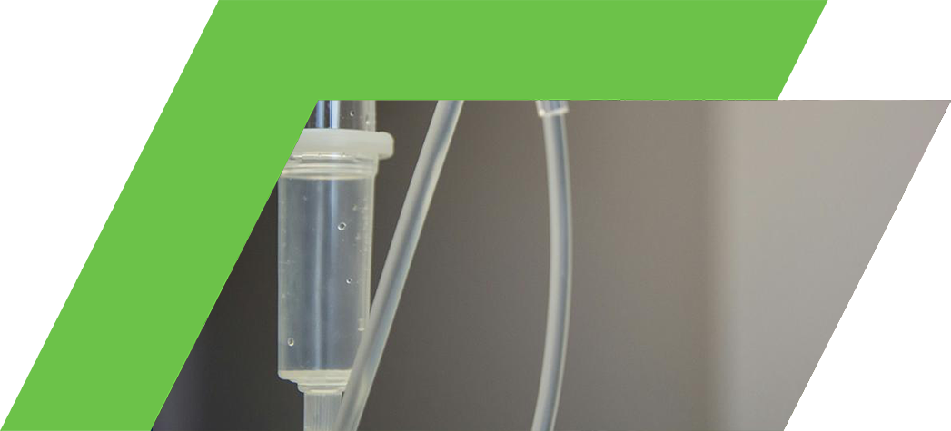 A close-up of an intravenous (IV) drip setup with clear tubing and a green connector.
