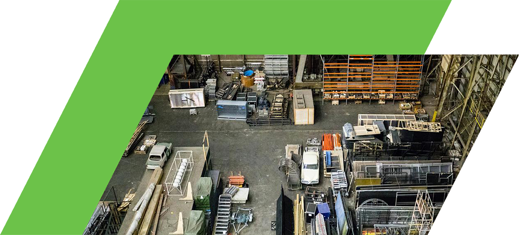 Aerial view of a large warehouse filled with various materials and equipment, including scaffolding, pipes, and storage containers.