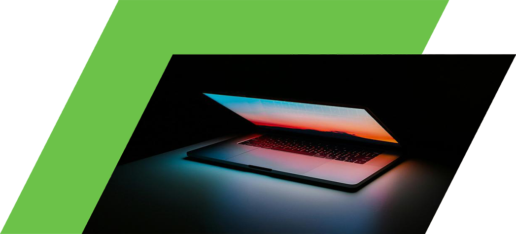 A laptop with a glowing screen displaying a colorful sunset, set against a dark background.