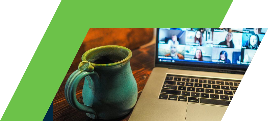 A green mug sits next to a laptop displaying a video conference with multiple participants on the screen.