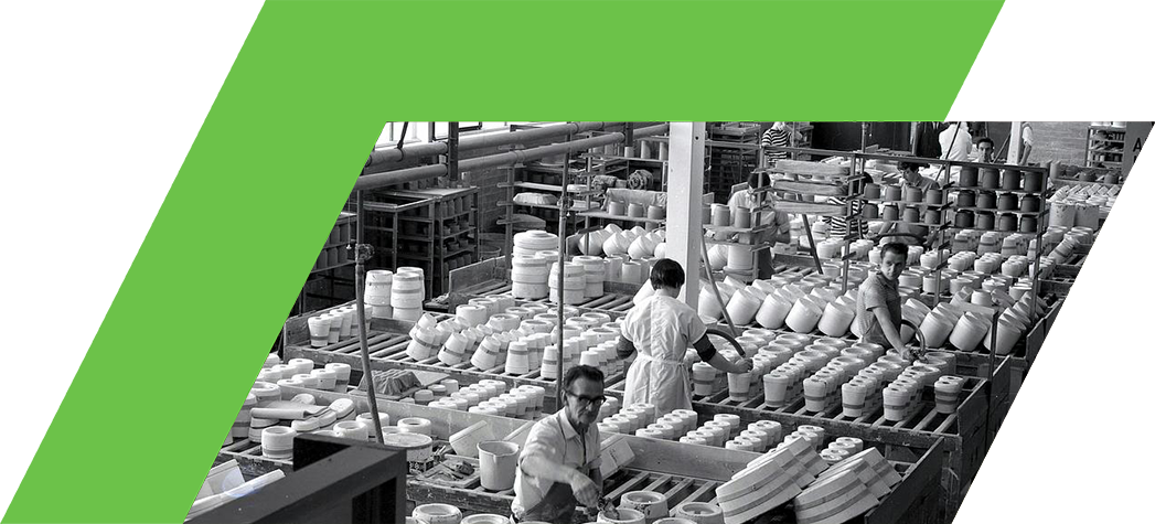 Workers assembling pottery in a large industrial factory setting.