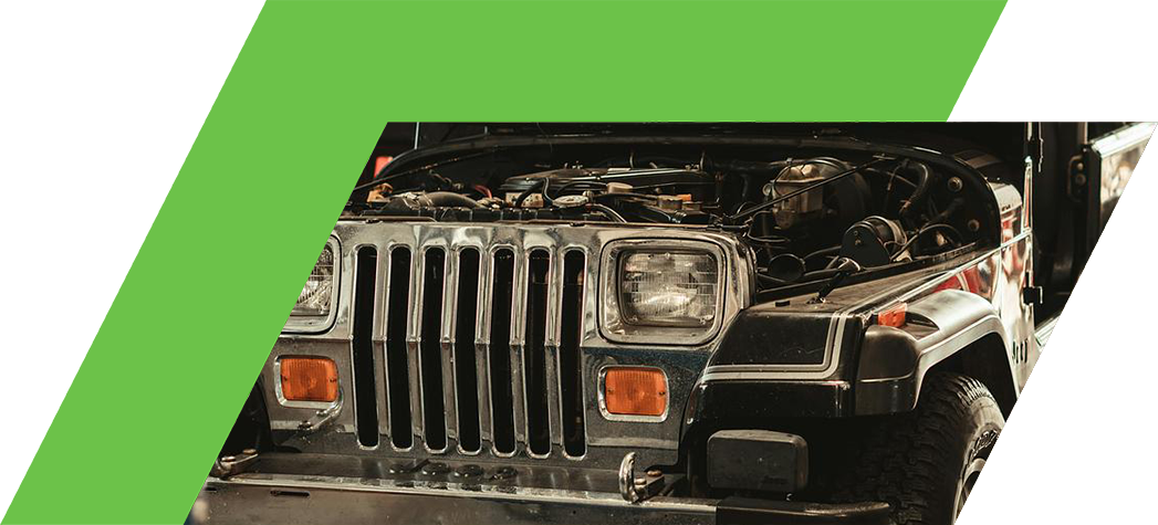 A vintage Jeep with its hood raised, revealing the engine compartment, is parked in a garage.