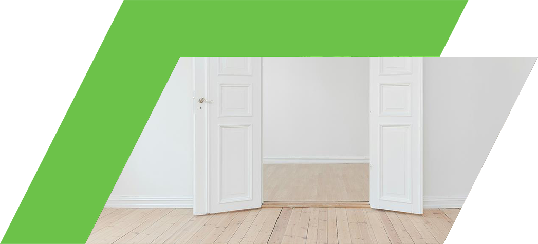 A view of an open doorway leading to a bright, empty room with wooden flooring.