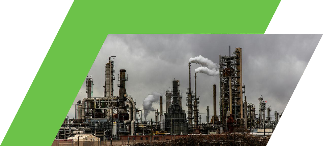 Industrial oil refinery with smokestacks emitting steam against a cloudy sky.