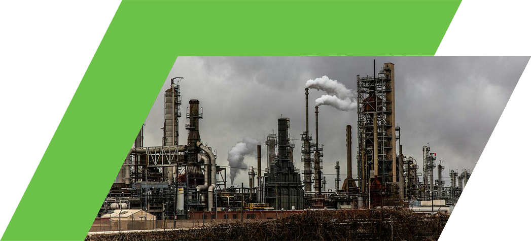 An industrial complex with tall smokestacks releasing smoke against a cloudy sky.