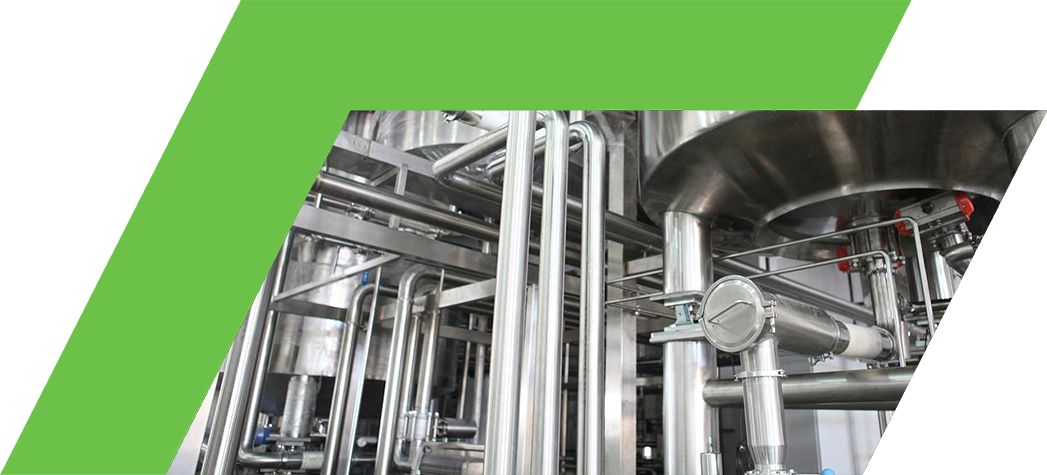Close-up of industrial stainless steel piping and tanks in a processing facility.