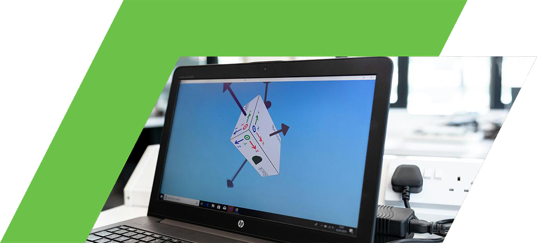 A laptop displays a 3D model with directional arrows on its screen, set in a bright, modern workspace.