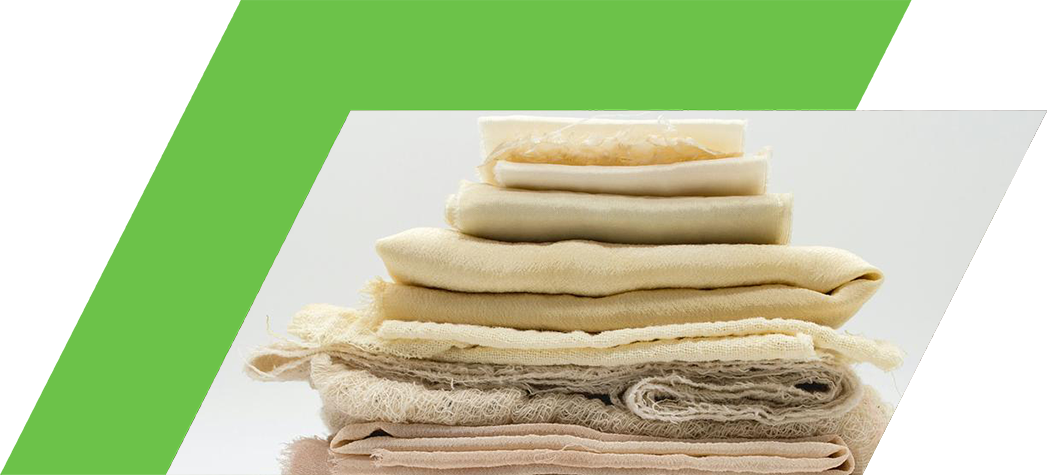 A neatly stacked arrangement of various textured fabrics in shades of cream, pink, and orange.