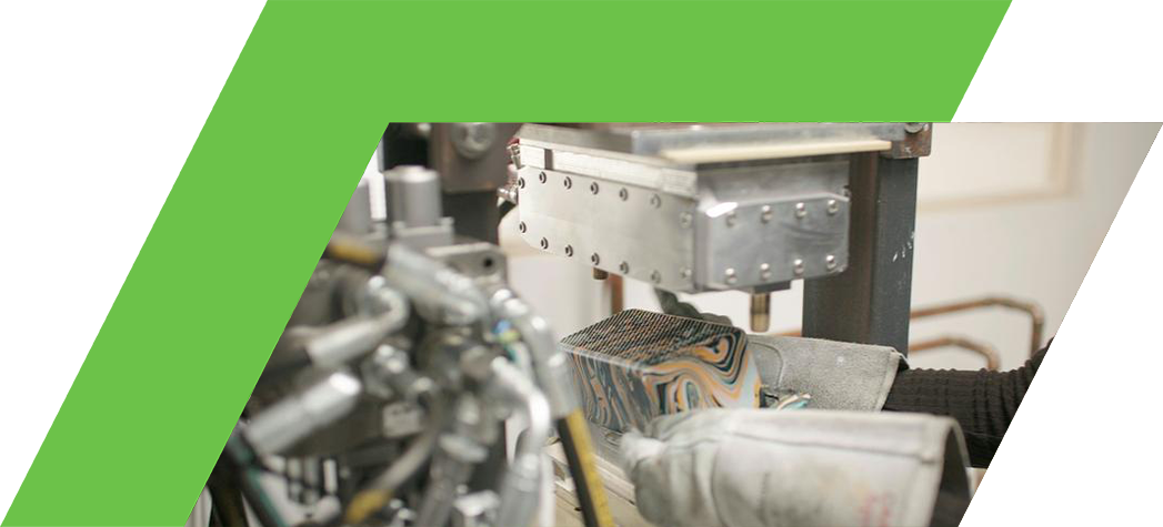 A person in gloves is operating a hydraulic press to mold a colorful, patterned object.
