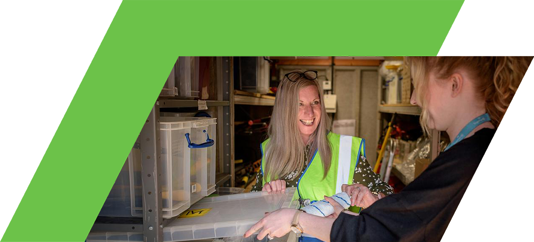 Two women interact while organizing storage boxes in a well-lit space.