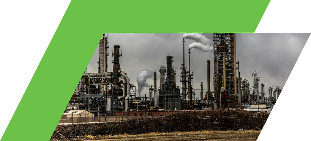 A large industrial complex with multiple smokestacks emitting steam under a cloudy sky.