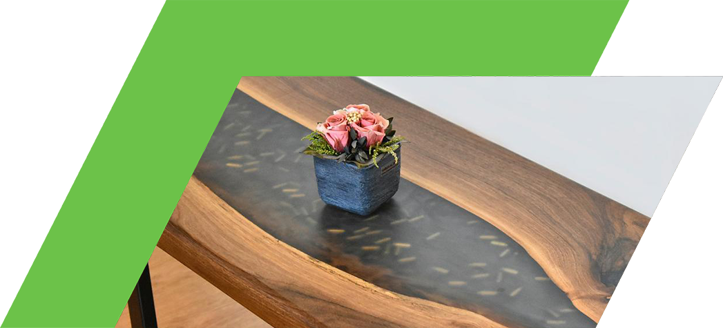 A beautifully crafted wooden table featuring a black resin inlay and a small potted flower arrangement on top.