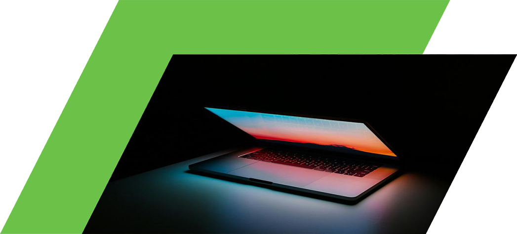 A laptop is illuminated against a dark background, displaying a colorful sunset on its screen.