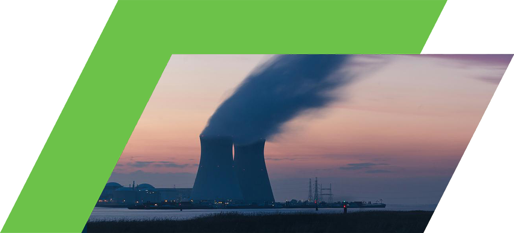 Nuclear power plant cooling towers emit steam against a colorful sunset sky.