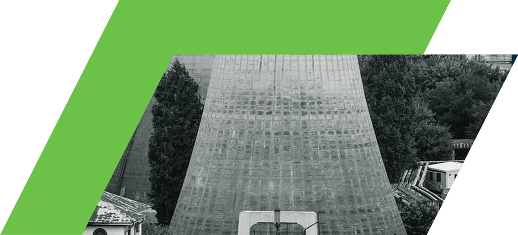 Black and white image of two cooling towers surrounded by urban buildings and greenery.