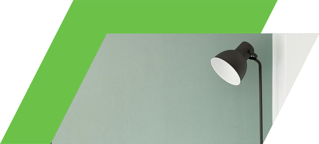 A minimalist black floor lamp stands against a muted green wall.