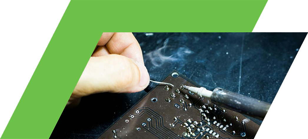 A person is soldering a component onto a circuit board with smoke rising from the soldering iron.