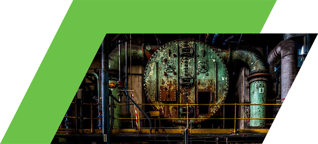 An industrial setting featuring large, rusted machinery and complex piping.