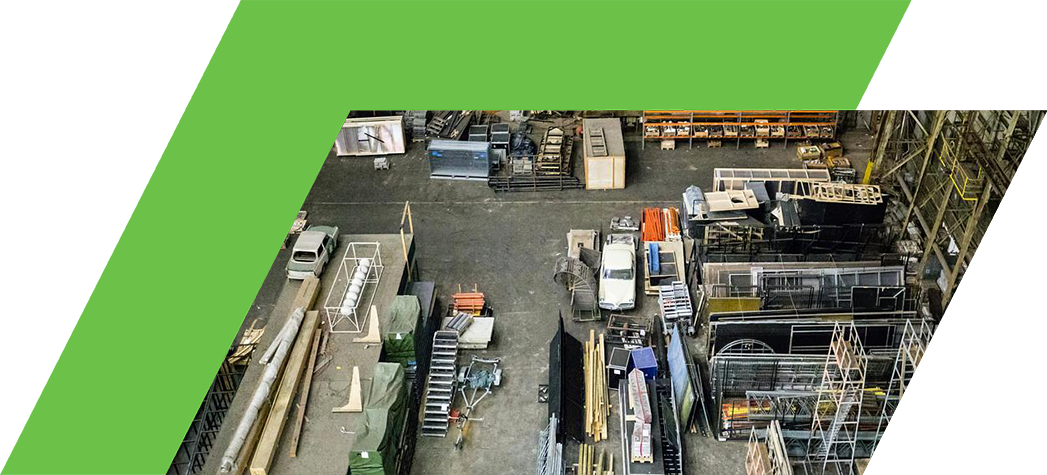 Aerial view of a large industrial warehouse filled with various stacks of materials, equipment, and containers.