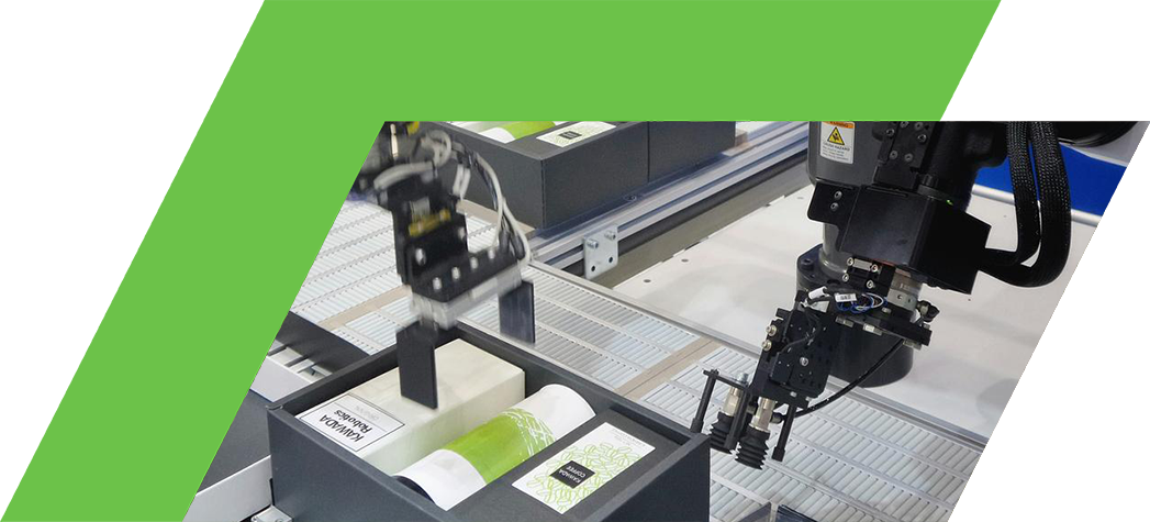 Two robotic arms are working on a conveyor belt, handling various packaged products in a manufacturing setting.