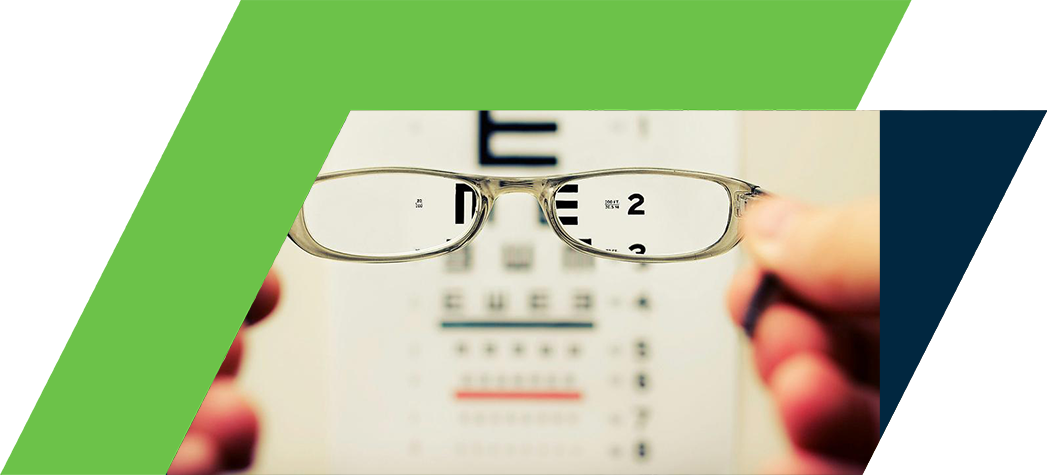 A person holds a pair of glasses in front of an eye chart displaying various letters and numbers.