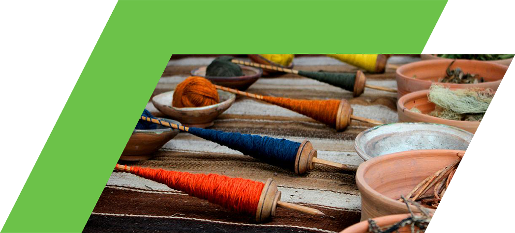 A colorful display of spindles and bowls filled with various natural fibers and herbs arranged on a woven textile.