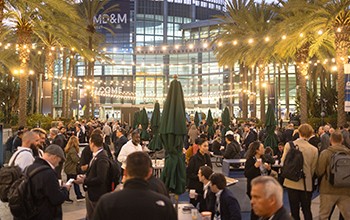 A diverse crowd of people gathered at an outdoor event, enjoying activities and socializing under a clear blue sky.